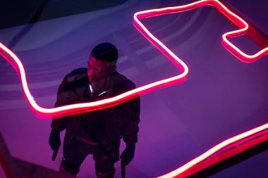 overhead view of armed bi-racial cyberpunk player holding guns near red neon lighting  clipart