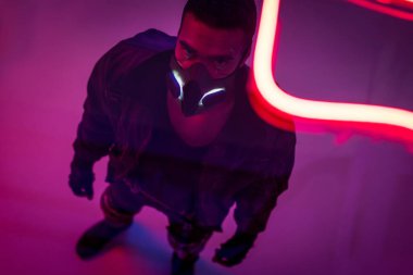 Kırmızı neon ışıklı maskeli çift ırklı siber punk oyuncusunun genel görünümü 