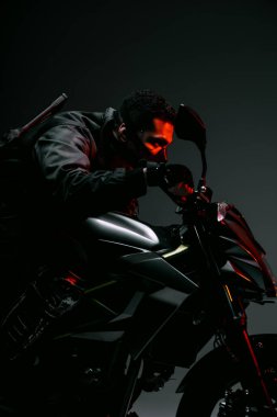 Gri üzerinde motosiklet süren maskeli çift ırklı siber punk oyuncunun yan görüntüsü 