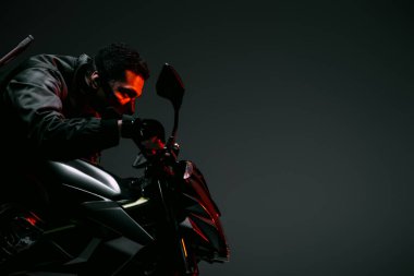 Gri üzerinde motosiklet süren maskeli tehlikeli çift ırklı siber punk oyuncunun yan görüntüsü 