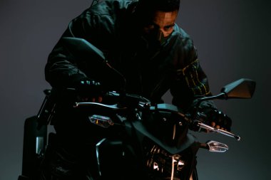 Gri üzerinde motosiklet süren maskeli karışık ırk siber punk oyuncusu 