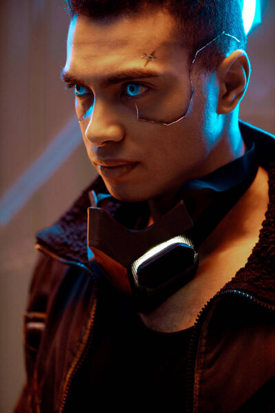 bi-racial cyberpunk player with metallic plates on face and blue eyes looking away near neon lighting 