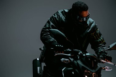 Maskeli karışık ırk siber punk oyuncusu ve gri üzerinde motosiklet süren fütüristik gözlüklü. 