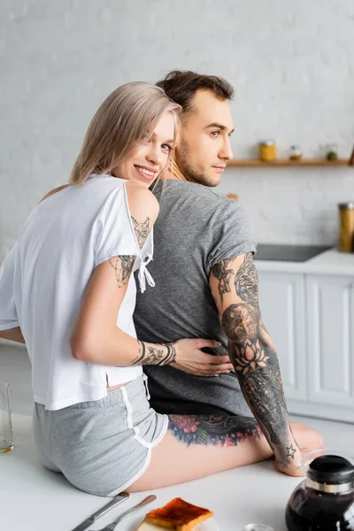 Menina Bonita Sorrindo Para Câmera Enquanto Abraçando Namorado Tatuado Durante — Fotografia de Stock