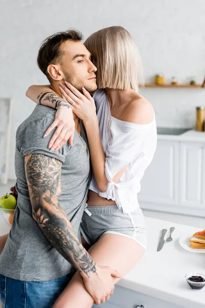 Side View Handsome Tattooed Man Hugging Girlfriend Kitchen Table Breakfast — Stock Photo, Image