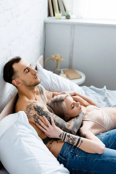 Όμορφη Γυναίκα Σουτιέν Αγγίζοντας Μυώδες Τατουάζ Φίλο Στο Κρεβάτι — Φωτογραφία Αρχείου