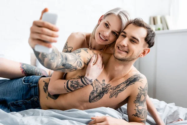 Selektivt Fokus Leende Tatuerade Par Tar Selfie Med Smartphone Sängen — Stockfoto