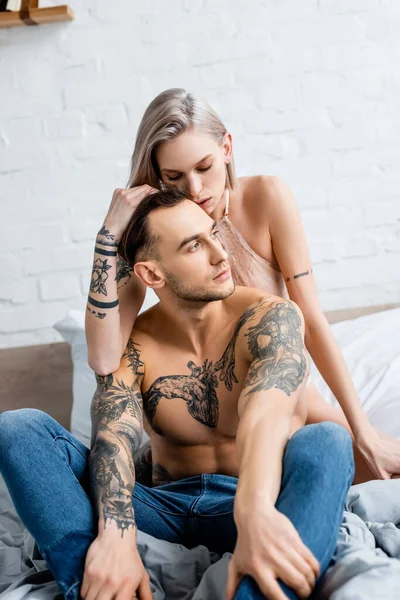 Vacker Kvinna Vidrör Håret Muskulös Tatuerad Pojkvän Sängen — Stockfoto