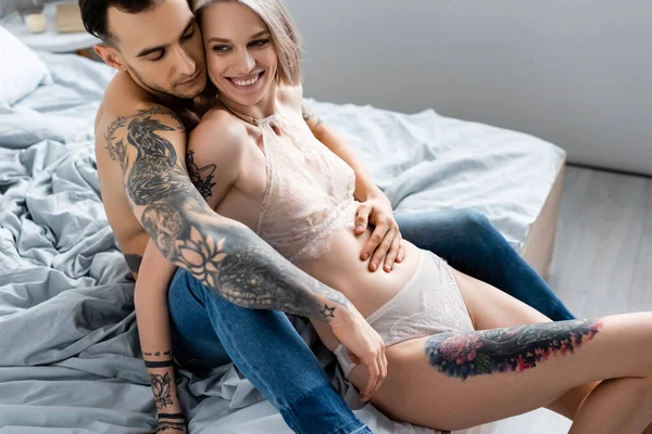 Shirtless Tatuado Homem Abraçando Bela Namorada Sorridente Lingerie Cama — Fotografia de Stock