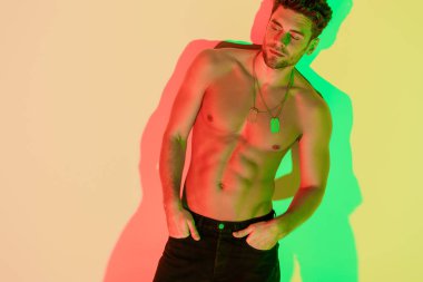Ceplerinde el ele tutuşan seksi, üstsüz adam kırmızı ve yeşil gölgeli sarıya bakıyor.