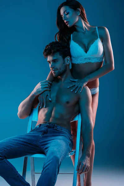 섹시하고 셔츠를 남자가 의자에 매력적 란제리를 여자가 배경에서 그를껴안고 있습니다 — 스톡 사진