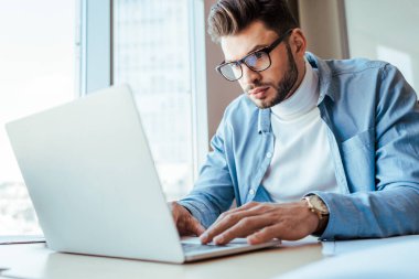 IT worker working with laptop at table in coworking space clipart