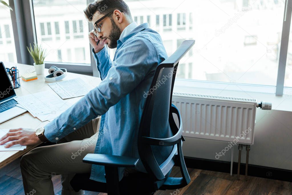 Thoughtful IT worker with documents at table in coworking space