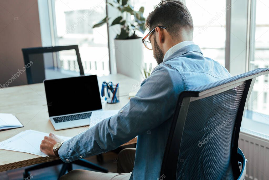 IT worker sitting in front of laptop at table in coworking space