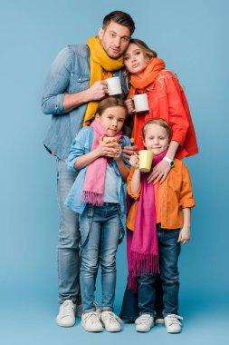Hasta ve çocuklu bir aile elinde sıcak içeceklerle mavi bardaklarla