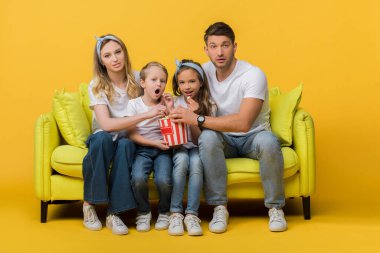 şaşırmış bir aile kanepede film izliyordu. Sarı mısır kovası vardı. 
