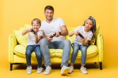 KYIV, UKRAINE - 4 Mart 2020: Mutlu baba ve çocuklar sarıda joysticklerle oyun oynuyorlar