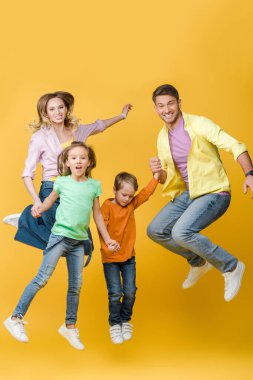 Heyecanlı aile zıplıyor ve sarıya el ele tutuşuyor