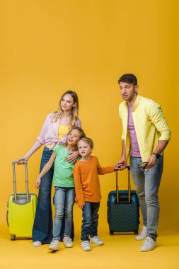 Mutlu aileler ve çocukların seyahat çantaları, pasaportları ve sarı biletleri.