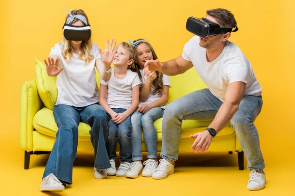 笑着和父母坐在沙发上 头戴黄色虚拟现实耳机的孩子 — 图库照片