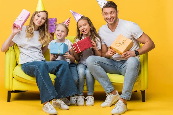 Cheerful Parents Kids Birthday Party Caps Holding Gift Boxes Sofa — Stock Photo, Image