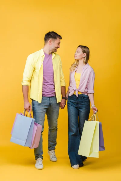 Beautiful Couple Holding Shopping Bags Looking Each Other Yellow — Stock Photo, Image