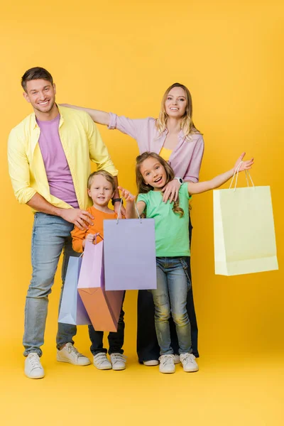 明るい両親と黄色のショッピングバッグで興奮した子供たち — ストック写真