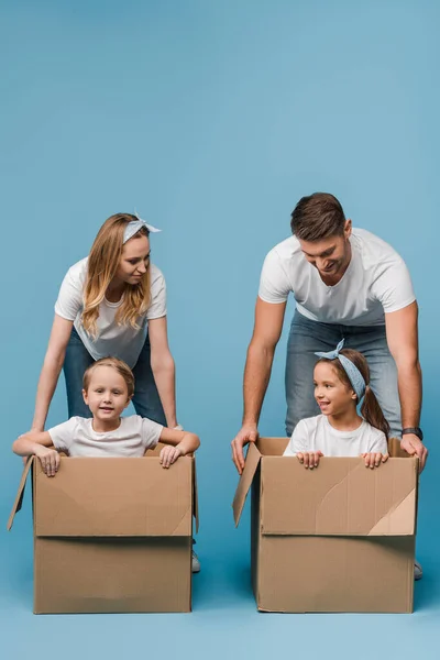 快乐的父母 带着快乐的孩子在纸板箱里蓝色地重新安置 — 图库照片