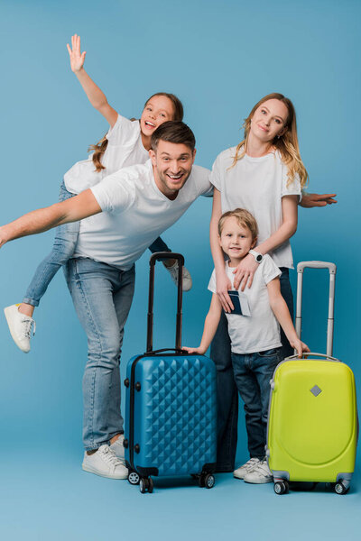 excited family of travelers with suitcases, passports and tickets on blue