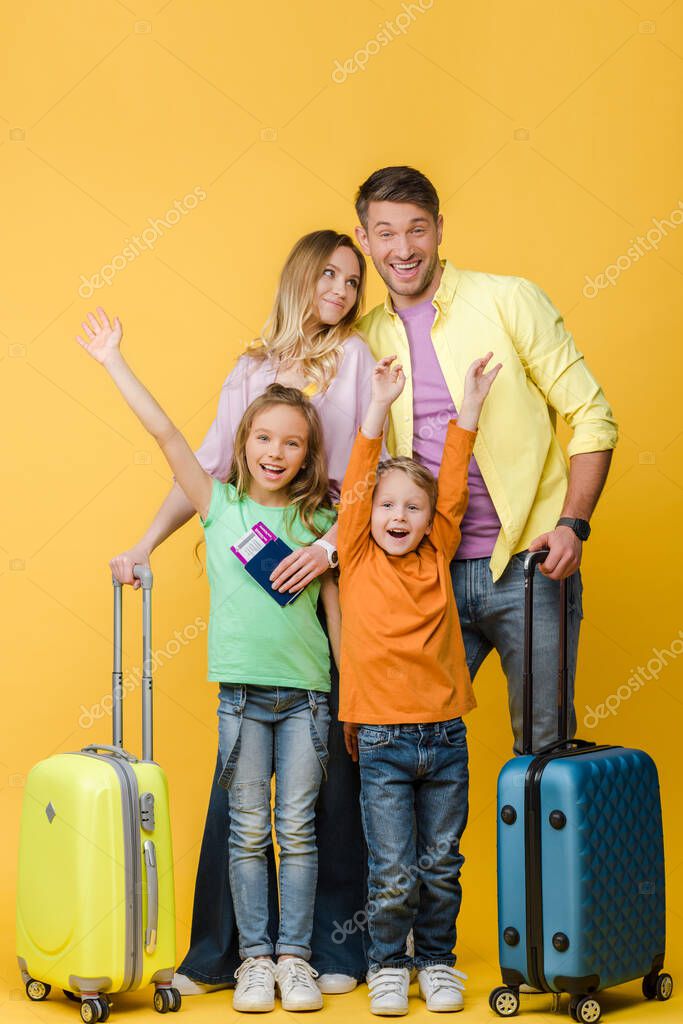 cheerful family of travelers with luggage, passports and tickets on yellow