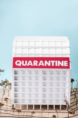 cardboard hospital model with quarantine lettering isolated on blue clipart