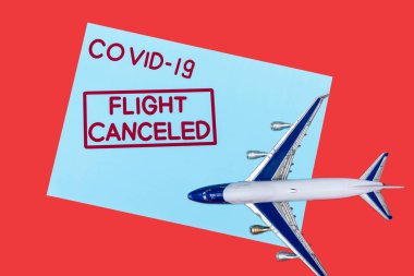 Mavi zarfın üst görüntüsü covid-19 ve uçuş iptal edildi kırmızı üzerinde izole oyuncak uçak yakını harfleri 
