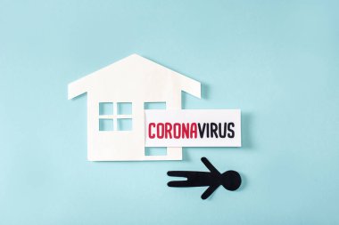 Kağıt ev ve Coronavirus yakınlarında mavi harflerle yazılmış insan görüntüsü.  