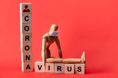 Küçük tıbbi maskeli manken, tahta küplerin yanında kırmızı harflerle Coronavirus yazılıydı. 