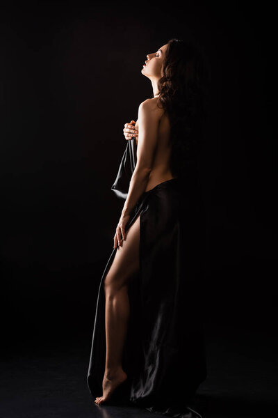 Attractive sexy nude woman in black cloth on black