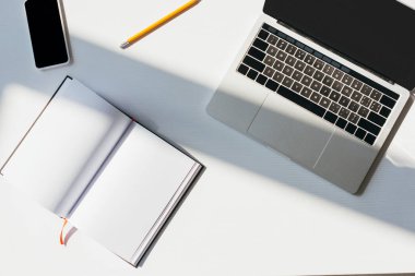 Bilgisayarlı, akıllı telefonlu, not defterli ve kalemli boş işyerlerinin en üst görünümü