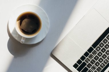 Bilgisayarlı boş işyeri manzarası ve güneş ışığında bir fincan kahve.