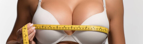 partial view of sexy girl measuring breasts with measuring tape isolated on white, panoramic shot