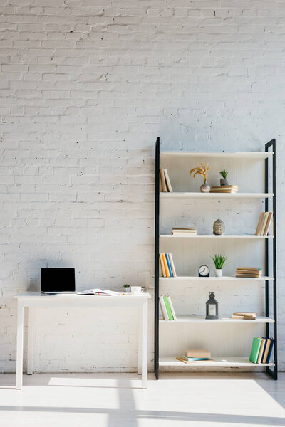 home office with book shelf and laptop on table in sunlight