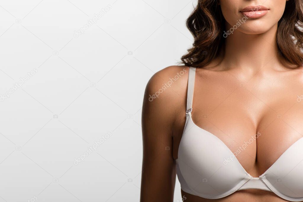 partial view of sexy girl with big breasts in white bra isolated on white