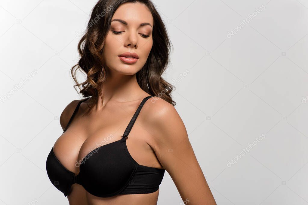 attractive, sexy girl with big breasts in black bra posing isolated on white