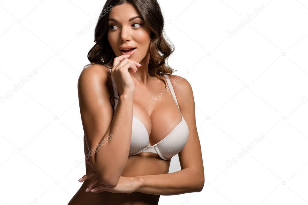 attractive surprised girl with big breasts looking away while touching lips isolated on white