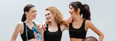 Beyazlara izole edilmiş spor aletleri olan mutlu ve çok kültürlü kızların panoramik çekimi 