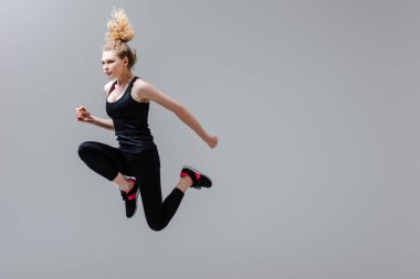 Spor giyimli kıvırcık kadın gri renkte atlıyor. 