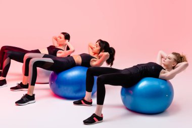 Çok kültürlü kızlar pembenin üzerinde spor yapıyor. 