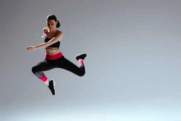 Привлекательная Женщина Спортивной Одежде Прыгает Сером — стоковое фото