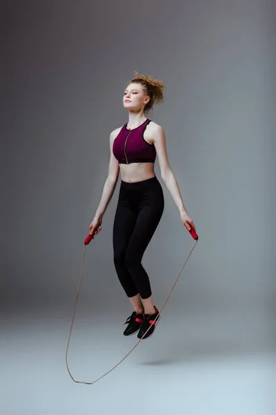 Lockige Frau Sportkleidung Springt Mit Springseil Auf Grau — Stockfoto