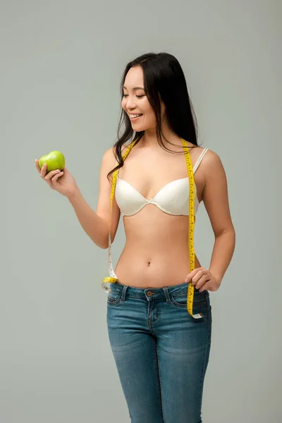 快乐而肥胖的亚洲女孩 手里拿着用灰色隔开的尺子和苹果 — 图库照片