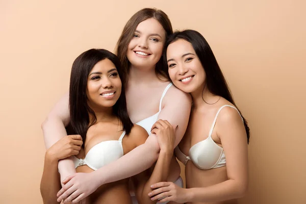 Sorrindo Mais Tamanho Multicultural Mulheres Sutiãs Abraçando Isolado Bege — Fotografia de Stock
