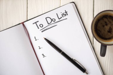 Top view of notebook with do list lettering and pen near cup of coffee on wooden background clipart